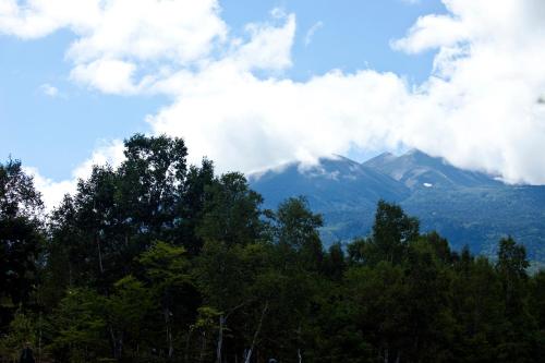 a view of a mountain with clouds and trees at Poetical in Matsumoto