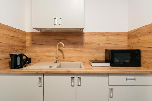 a kitchen counter with a sink and a microwave at ORSO Rooms & Apartments - LoftAffair Collection in Warsaw