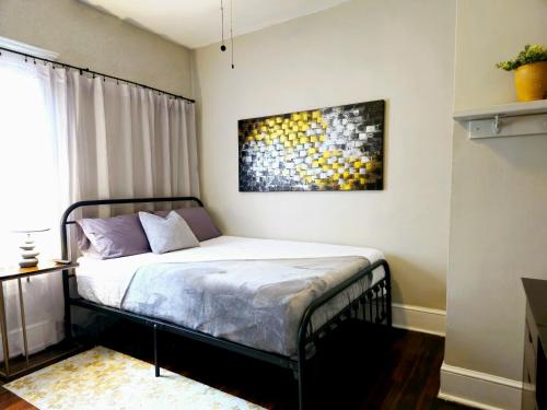 a bedroom with a bed with a painting on the wall at Charming! near CLE Clinic/UH/CWRU/Dwntwn w/porch in Cleveland