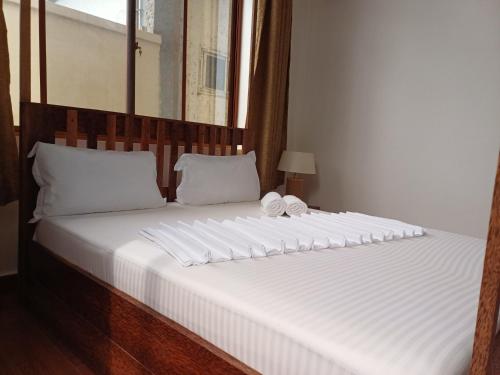 uma grande cama branca com uma cabeceira em madeira e almofadas brancas em Jodari Hotel Nungwi em Nungwi