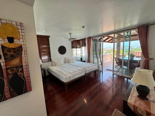 スリンビーチにあるSurin Sabai Condo - Phuketのベッドルーム(大型ベッド1台、バルコニー付)