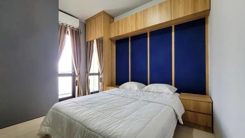 a bedroom with a large bed with a blue wall at Palam Mansion at Apartment One Residence in Batam Center