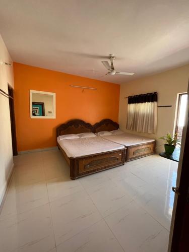 a bed in a room with an orange wall at Hotel Raghunath residency -Niwas in Shirdi