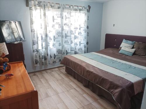 Schlafzimmer mit einem Bett, einem Tisch und einem Fenster in der Unterkunft Casa de mamá in Santa María Azompa