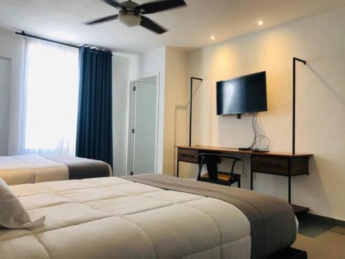 a bedroom with two beds and a desk with a television at Urban Gran Plaza in Guadalajara