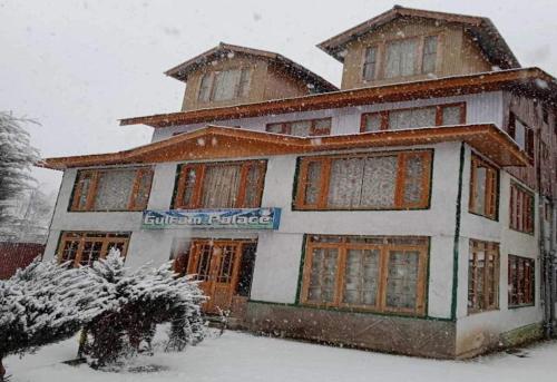 a building covered in snow in front at Hotel Gulfam Palace in Pahalgām