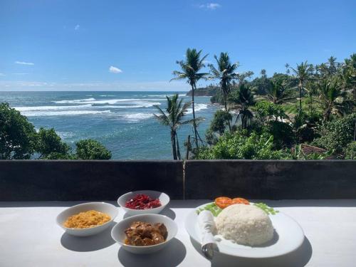 a table with bowls of food and the ocean at The Reef Weligama in Weligama