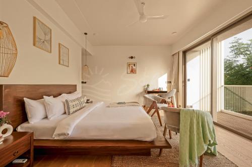a bedroom with a bed and a desk and a window at The Banyan Tree Villa A4 by Stay ALYF, Siolim in Siolim