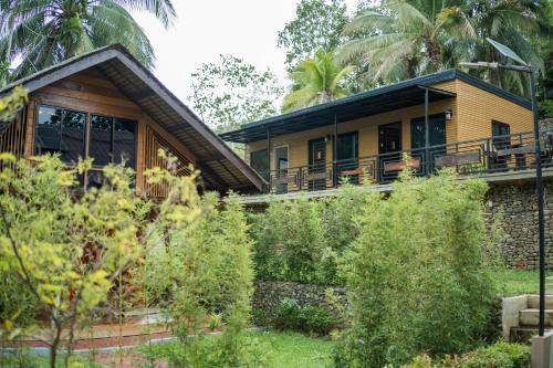 a yellow house with a balcony and trees at Daya Farm and Adventure in Banay-Banay