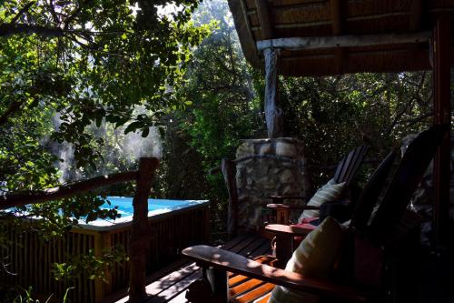 a patio with a hot tub and chairs on a deck at Mosaic Lagoon Lodge in Stanford