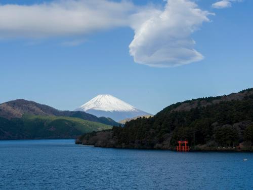 a mountain in the background of a lake with a red object at Rakuten STAY FUJIMI TERRACE 箱根芦ノ湖　 in Moto-hakone