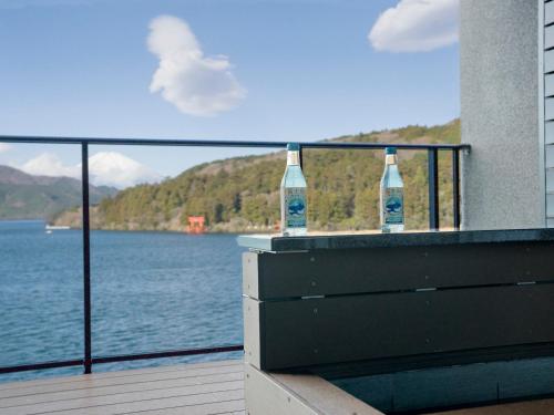 two bottles sitting on a balcony overlooking a body of water at Rakuten STAY FUJIMI TERRACE Hakone Ashinoko in Hakone