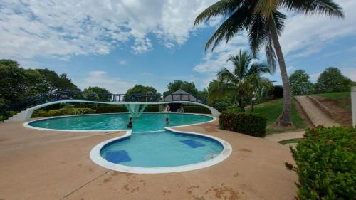 a swimming pool with a bridge and a palm tree at Casa Vacacional en Condominio Via Melgar-Carmen de Apicalá in Melgar