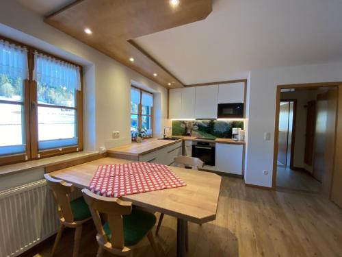 eine Küche mit einem Holztisch mit einem roten und weißen karierten Tischtuch in der Unterkunft Hemerhof in Oberstdorf