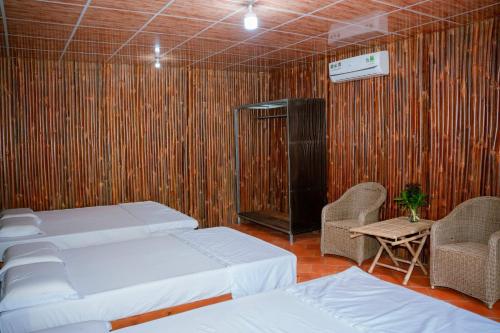 a room with two beds and a tv and chairs at HƯNG THÀNH HOME in Ben Tre