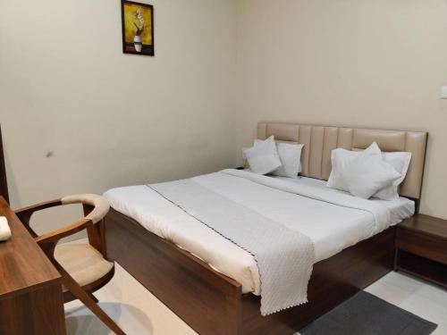 Cette chambre comprend un lit avec des draps blancs et une chaise. dans l'établissement Hotel Raipur Pride, à Raipur