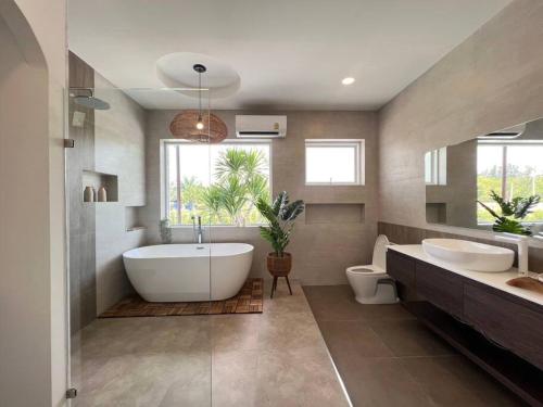 a bathroom with two sinks and a tub and a toilet at Arom Pool Villa Pattaya 2 in Na Jomtien