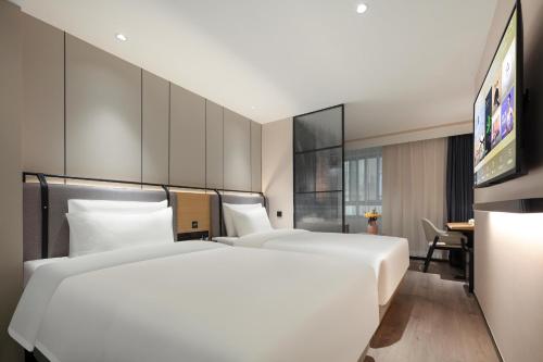 Atour X Hotel Shanghai Xujiahui Sports Center في شانغهاي: غرفة فندقية بسريرين ومكتب