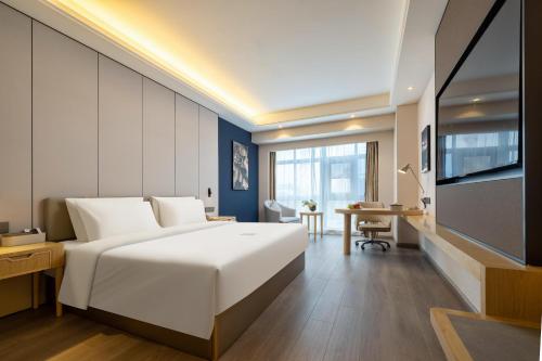a bedroom with a large white bed and a desk at Atour X Hotel Shenzhen Baoan Airport Aviation City in Bao'an