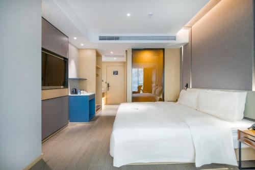 een slaapkamer met een groot wit bed en een televisie bij Atour Hotel Guangzhou Sanyuanli in Guangzhou