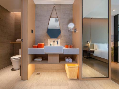 ein Badezimmer mit einem Waschbecken, einem WC und einem Spiegel in der Unterkunft Atour Hotel Foshan Shunde Happy Coast in Shunde