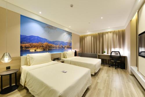 a hotel room with two beds and a large painting on the wall at Atour Hotel Olympic Sports Center Bird's Nest in Beijing
