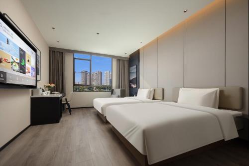 a hotel room with two beds and a flat screen tv at Atour Hotel Xiamen Xiang'an Torch Industrial Park in Xiang'an