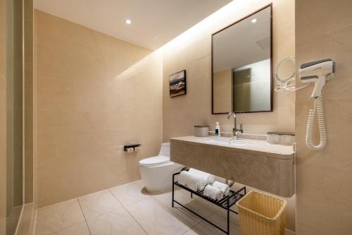 a bathroom with a sink and a toilet and a mirror at Atour X Hotel Shenzhen Baoan Airport Aviation City in Bao'an