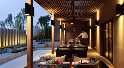 a man standing in front of a restaurant with tables at Atour Hotel Hangzhou Huanglong in Hangzhou