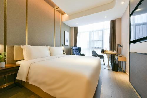 a hotel room with a large white bed and a desk at Atour Hotel Wangjing SOHO in Beijing