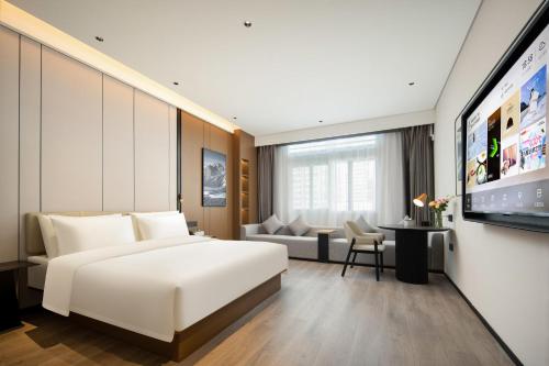 a hotel room with a large white bed and a couch at Atour Hotel Huizhou Huiyang New Metropolis in Huizhou