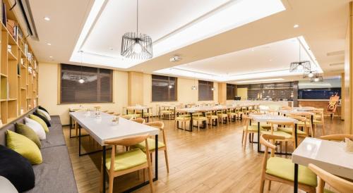 Atour Hotel Huaxiang Tiantan Hospital في بكين: مطعم فيه طاولات وكراسي في الغرفة