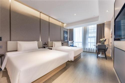 a hotel room with two beds and a desk at Atour Hotel Zhijiang Bridge in Hangzhou