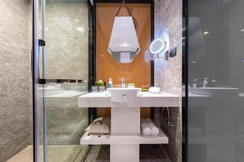 uma casa de banho com um lavatório e uma cabina de duche em vidro. em Atour Hotel Shenzhen Baoan Xixiang em Bao'an