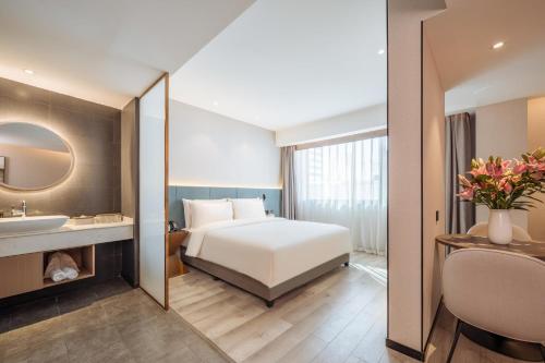 Schlafzimmer mit einem Bett, einem Waschbecken und einem Spiegel in der Unterkunft Atour X Hotel Kunming Cultural Palace East Renmin Road in Kunming
