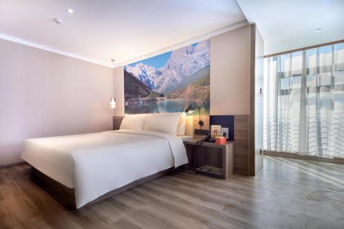 a bedroom with a large bed and a large window at Atour Hotel Kunming South High Speed ​​Railway Station University Town in Kunming