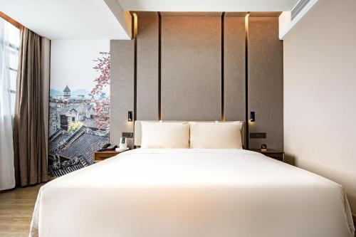 a bedroom with a large white bed and a window at Atour Hotel Guangzhou Panyu City Bridge in Guangzhou