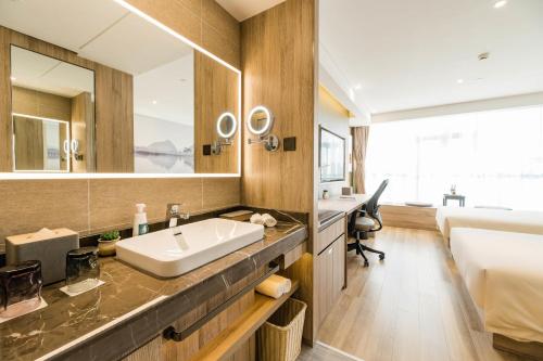 a bathroom with a sink and a bed at Atour Hotel Kunming Dashanghui in Kunming