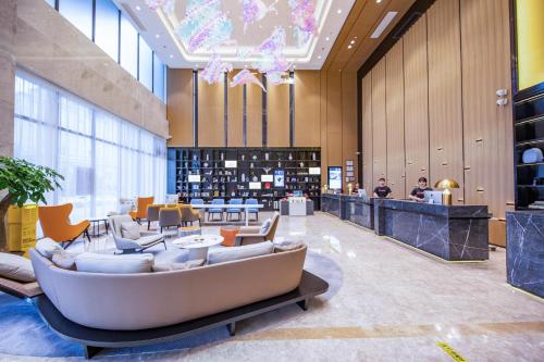 een lobby van een hotel met een bank en stoelen bij Atour Hotel Dongguan Fenggang in Qinglinjing