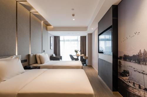 Atour Hotel Hangzhou West Lake Wulin Plaza North Jianguo Road في هانغتشو: غرفة فندقية بسريرين وتلفزيون