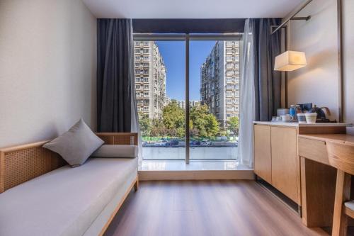 una camera con divano e ampia finestra di Atour X Hotel Beijing Haidian Sijiqing a Pechino