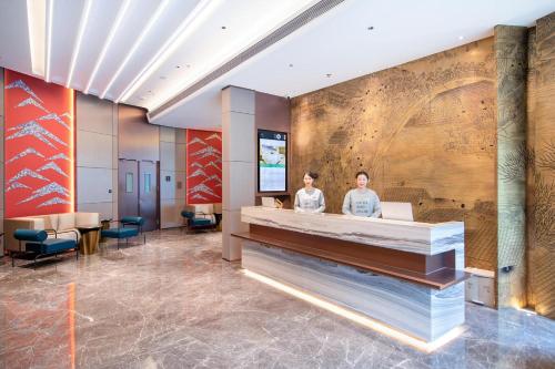 two people standing at a reception desk in a lobby at Atour S Hotel Beijing Daxing International Airport in Daxing