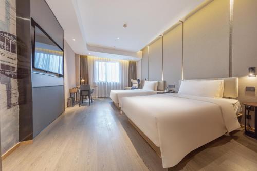 上海市にあるAtour Hotel Shanghai Caohejingのベッド2台とテーブルが備わるホテルルームです。