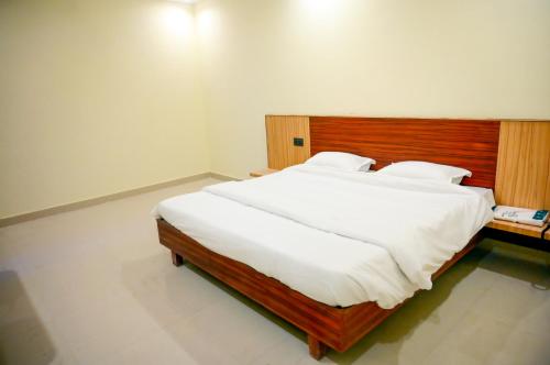 um quarto com uma grande cama branca e uma cabeceira em madeira em Sri Ram Janki Palace em Faizābād