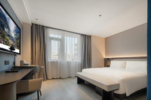 重慶市にあるAtour Light Hotel Chongqing Yuzhong Daping Metro Stationの大きなベッドとデスクが備わるホテルルームです。