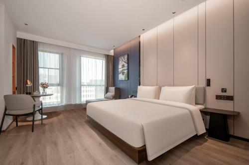 a bedroom with a large white bed and a desk at Atour Hotel Hangzhou East Railway Station East Square in Hangzhou