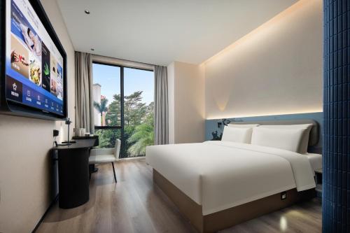 Schlafzimmer mit einem großen weißen Bett und einem Flachbild-TV in der Unterkunft Atour Light Hotel Guangzhou Pazhou Exhibition Canton Tower Subway Station in Guangzhou