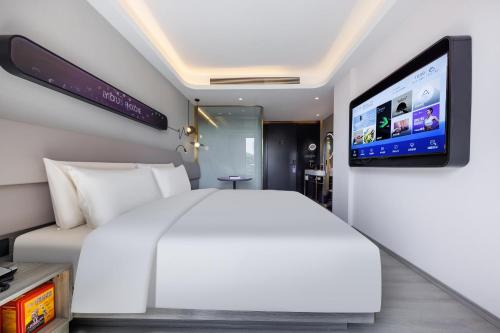 a bedroom with a white bed and a flat screen tv at Atour Light Hotel Zhuguang Road Hongqiao National Exhibition and Convention Center in Shanghai
