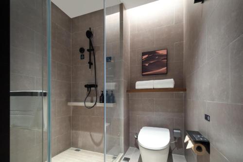a bathroom with a toilet and a glass shower at Atour Hotel Xiamen Xiang'an Torch Industrial Park in Xiang'an