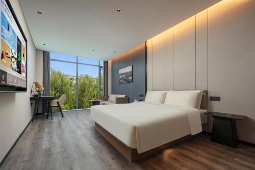 - une chambre avec un grand lit blanc et un bureau dans l'établissement Atour Hotel Hangzhou Zhejiang University Xilianqiao, à Hangzhou